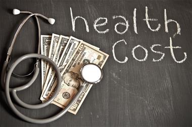 US Currency with health cost written in chalk on wood